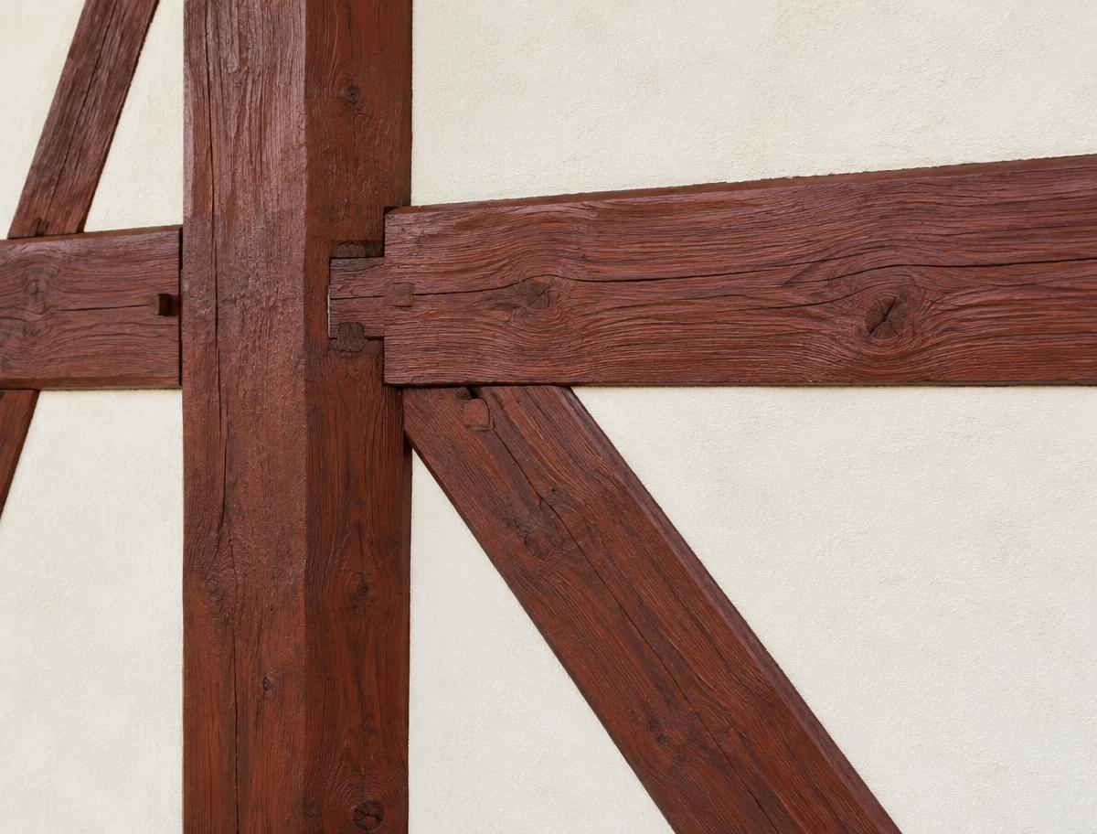 Aufgearbeitete Fachwerkbalken mit rotbrauner Beschichtung und erkennbarer Holzstruktur